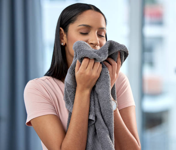 Shot of a young woman smelling a towel at home When all else fails, cleaning house is the perfect antidote Soft Washing stock pictures, royalty-free photos & images