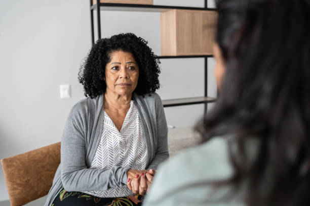 mãe séria ouvindo filha em casa ou fazendo uma consulta de psicologia - senior women depression sadness women - fotografias e filmes do acervo