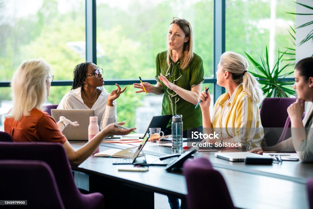 Whats Your Thoughts A wide-angle view of a board room meeting which is all women. They are discussing ideas and working on things together to come up with business opportunities. Sustainable Lifestyle Stock Photo