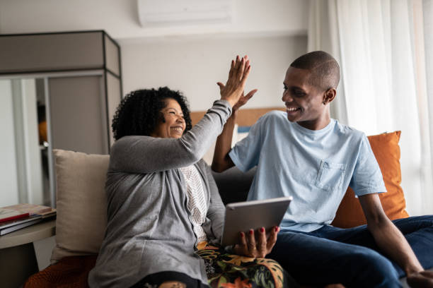 Grandmother and grandson doing a high five while using digital tablet at home