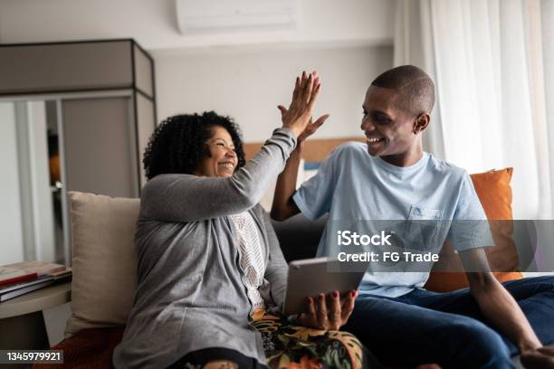 Grandmother and grandson doing a high five while using digital tablet at home
