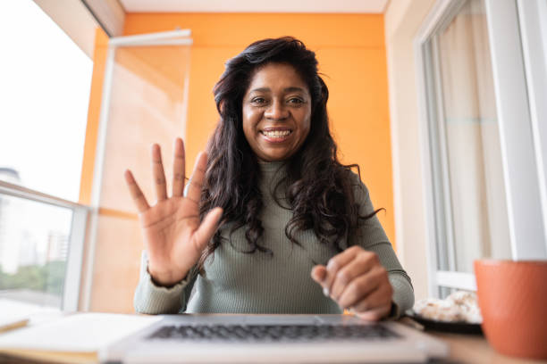 donna matura su una videochiamata sul laptop a casa - punto di vista della webcam - solo una donna matura foto e immagini stock