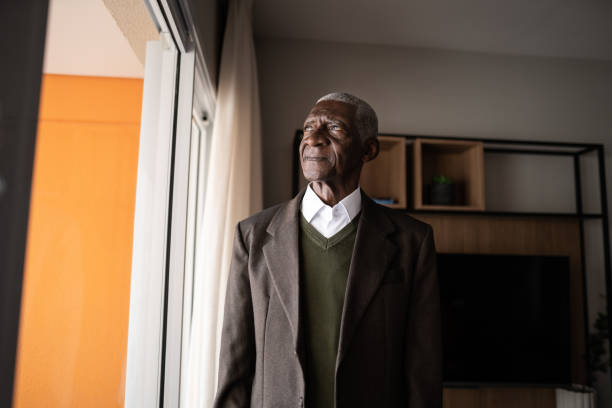 istock Contemplative senior man looking through the window at home 1345980165