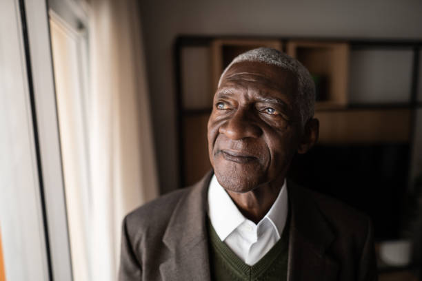 istock Contemplative senior man looking through the window at home 1345980179