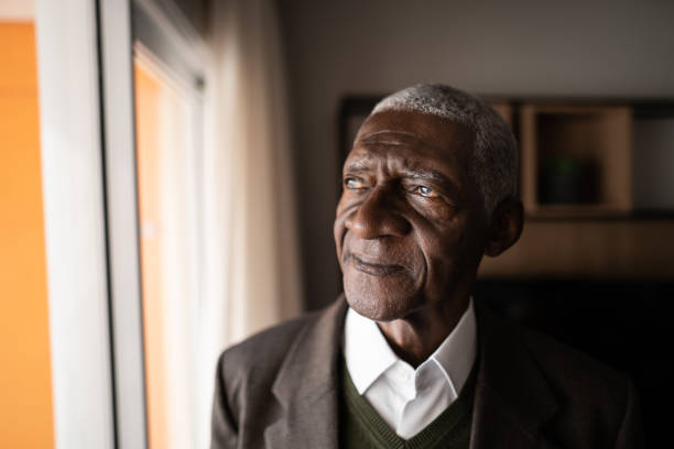 istock Contemplative senior man looking through the window at home 1345980187