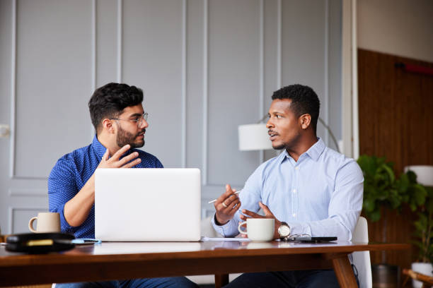 istock Diverse businessmen discussing work while sitting at a table in a home office 1345981351
