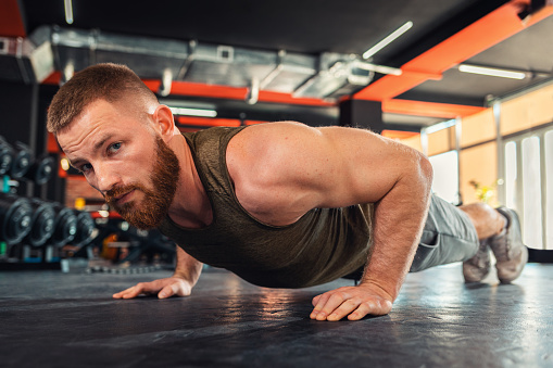 Portrait of young bearded athletic man doing push-ups in the gym. Close-up. The concept of fitness and training.