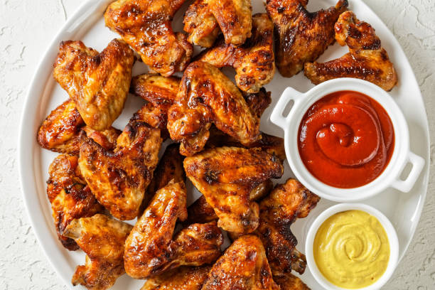 istock crispy roasted chicken wings served on a white platter with ketchup and mustard on a light textured table, flat lay, close-up 1345984000