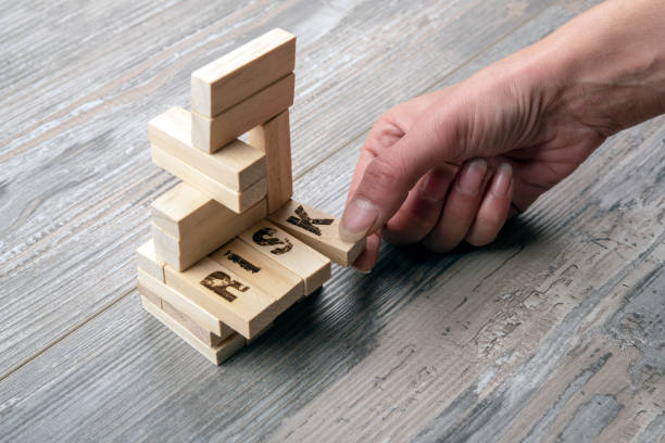 Taking one block from wooden blocks tower stock photo