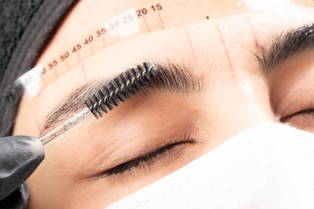 Beautician is applying permanent make up Beautician is using a eyebrow brush. Beautiful young woman in beauty salon on eyebrow makeup treatment. Beautician doing eyebrows tattooing. Ruler permanent makeup before and after stock pictures, royalty-free photos & images