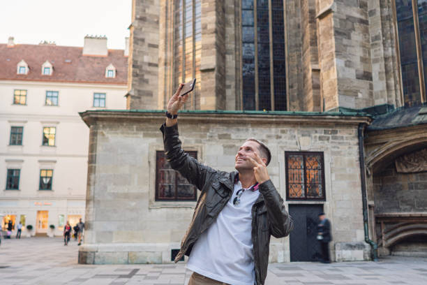istock Male torusit gesturing the peace sigh, while taking selfie in front of the St. Stephens Cathedral in Vienna 1345988845