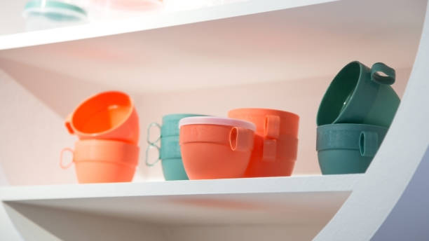 istock Various plastic new empty reusable mugs. Cookware in trendy pastel colors. Industrial background, kitchen interior 1345989144