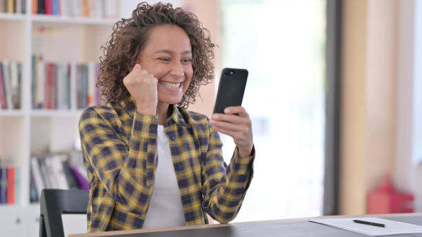 istock Indian Woman Cheering on Smartphone at Work, Success 1345990133