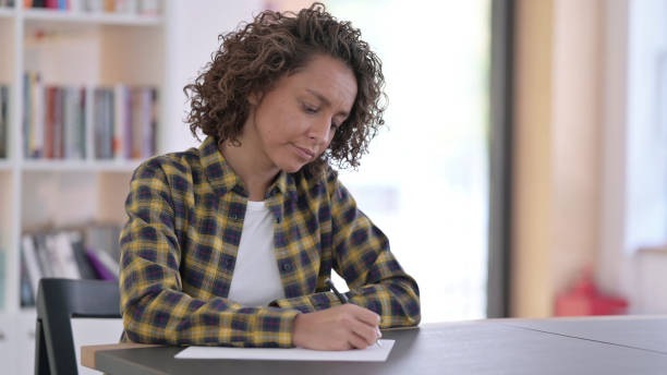 istock Young Indian Woman Writing on Paper at Work 1345990258