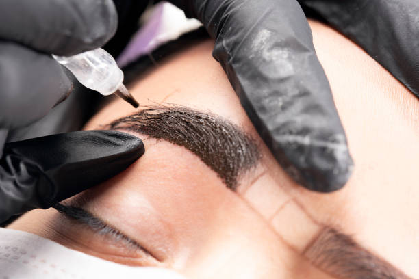 Beautician is applying permanent make up Beautician is using a machine. Beautiful young woman in beauty salon on eyebrow makeup treatment. Beautician doing eyebrows tattooing. permanent marker photos stock pictures, royalty-free photos & images