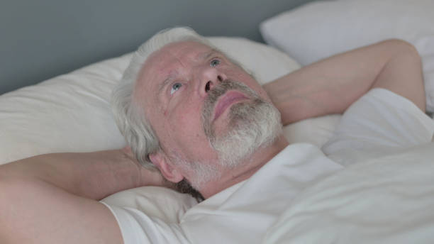 istock Serious Senior Old Man Laying Awake in Bed 1345994021