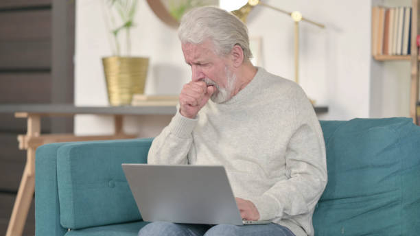 istock Senior Old Man with Laptop Coughing  at Home 1345994041