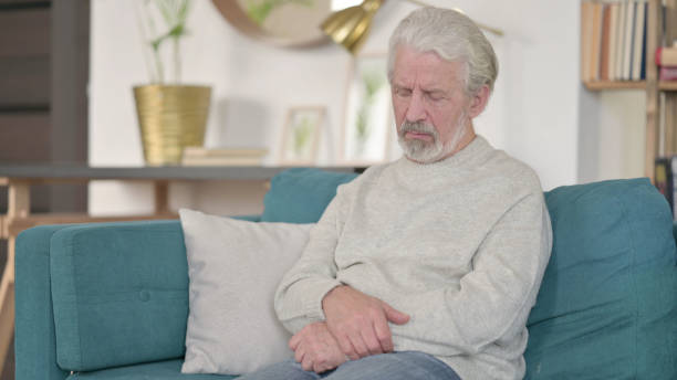 istock Sleepy Senior Old Man taking Nap Sitting at Home 1345994700