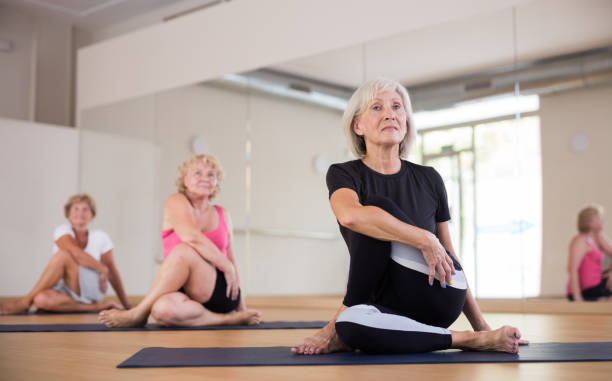 istock Aged woman doing twisting asana Matsyendrasana in yoga studio 1345995535