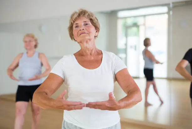 Photo of Elderly woman practicing ballet dance moves in choreographic studio