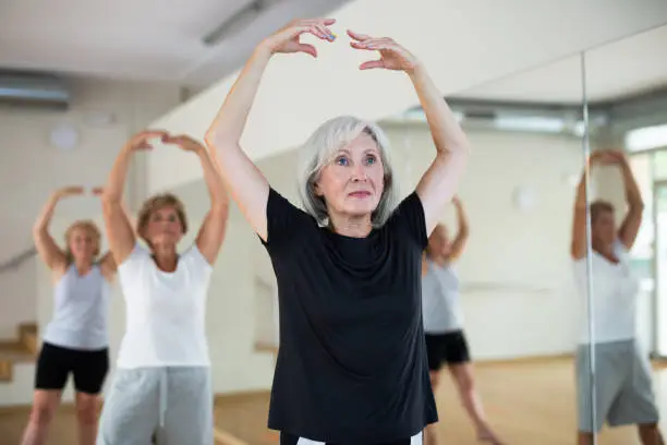 Photo of Aged woman practicing ballet dance moves in choreographic studio