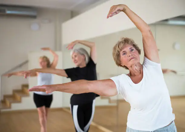 Photo of Senior lady learning classic dance moves during group class