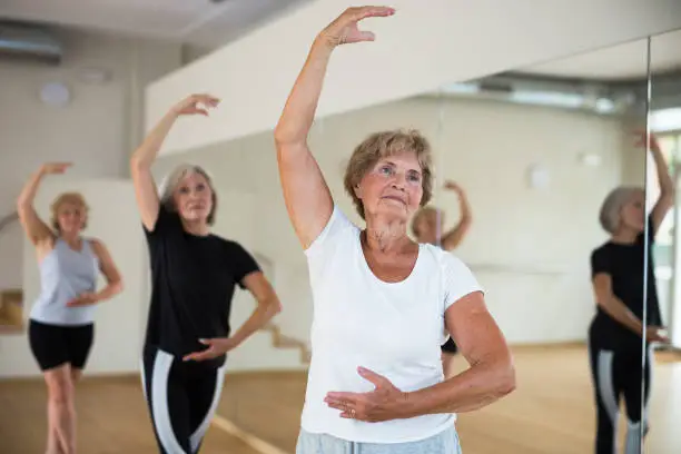 Photo of Elderly woman practicing ballet dance moves in choreographic studio
