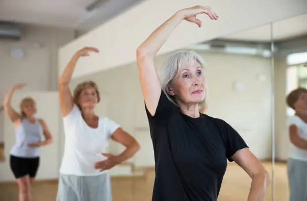 Photo of Aged woman practicing ballet dance moves in choreographic studio
