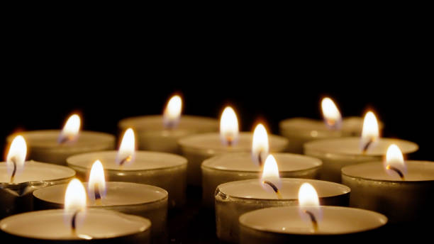 istock Close up burning tea lights isolated on black background 1345995863