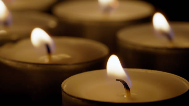 istock Close up burning tea lights isolated on black background 1345995900