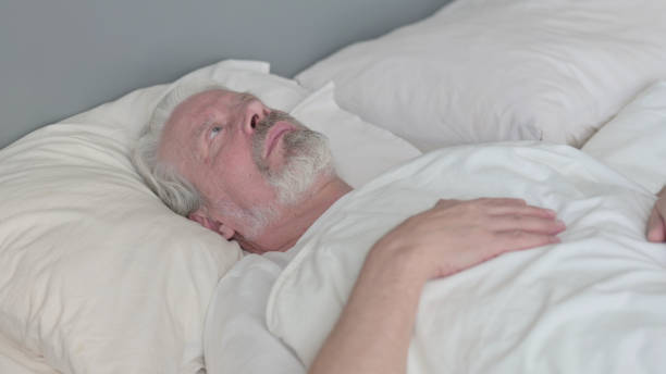 istock Pensive Senior Old Man Laying in Bed Thinking 1345995978