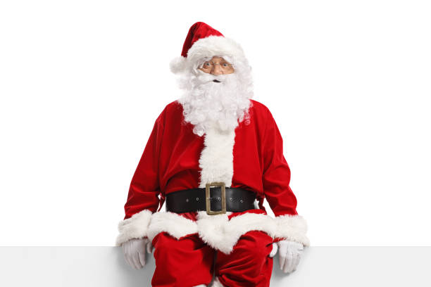 istock Santa claus sitting on a white banner and looking at camera 1345996276