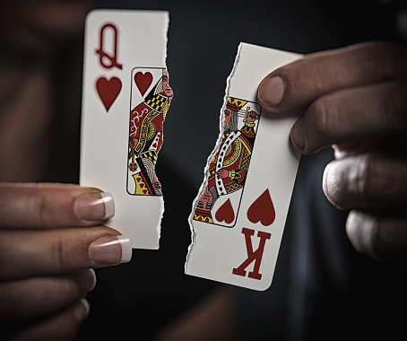 Man and woman symbolize their separation with raggedly torn king and queen cards.