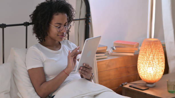 istock Young African Woman using Tablet in Bed 1345997449