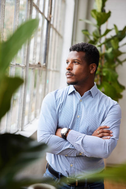 istock Young businessman deep in thought while looking out of his office window 1345997468