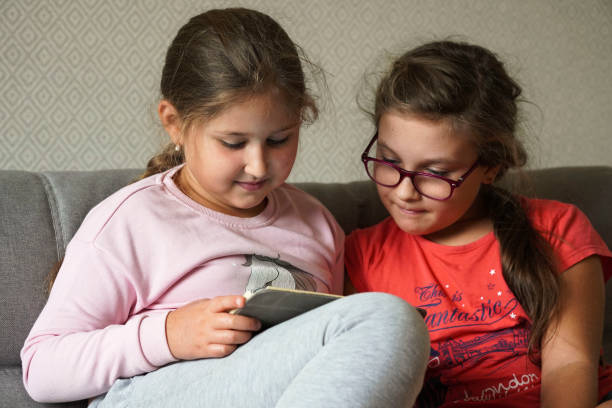 istock Two little girls sisters play on a tablet pc. 1345997625