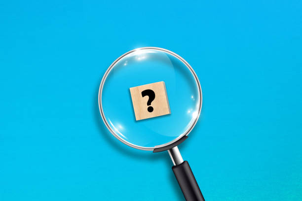 istock Magnifying glass and question mark on wooden block with blue background 1345997881