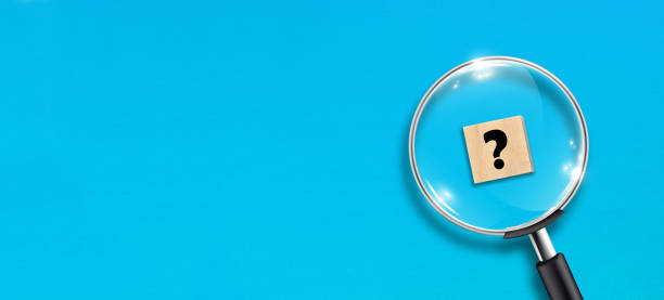 istock Magnifying glass and question mark on wooden block with blue background 1345997909