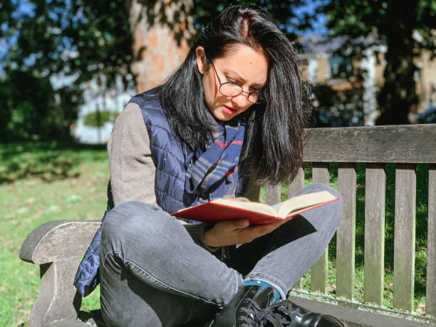 istock Young woman is reading book in park 1345998116