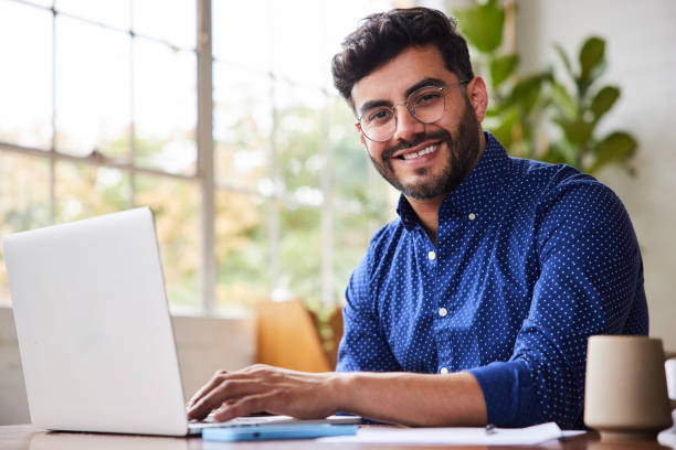 istock Young businessman smiling while working from home on a laptop 1345999682