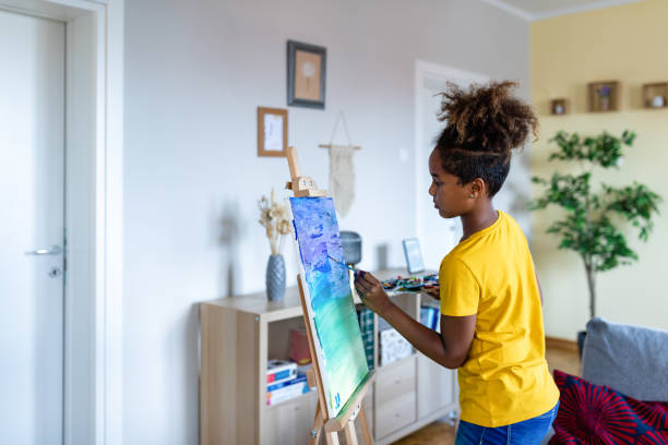 現代の抽象油絵に取り組む才能のある小さな黒人の女の子のアーティストは、広いストロークでブラシでジェスチャー。芸術的なパレット。 - artists canvas palette paintbrush oil painting ストックフォトと画像