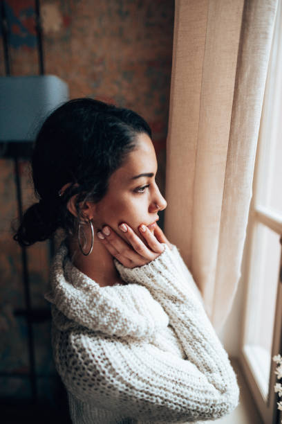 istock pensive woman looking at the window 1346006056
