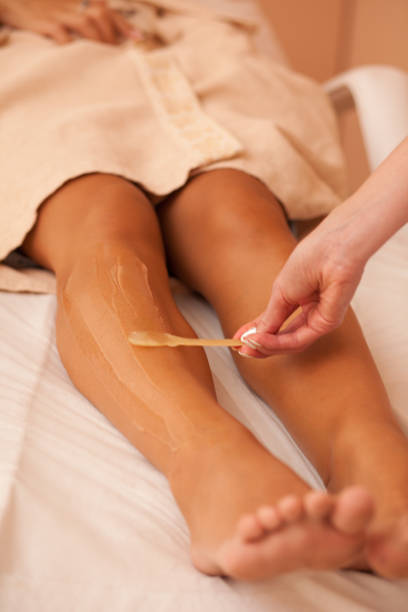 esteticista depilándose las piernas femeninas en el centro de spa - leg waxing fotografías e imágenes de stock