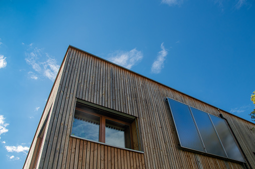 Solar collectors perpendicular to the wooden facade in front of a blue sky. High quality photo