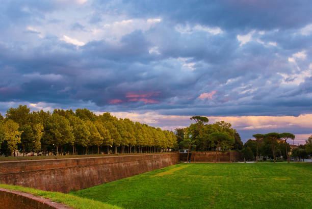Lucca ancient walls park with dramatic sky at sunset