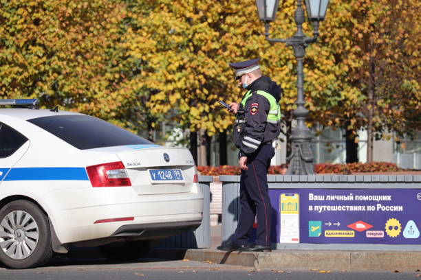 policier masqué debout sur la route avec smartphone près de la voiture - car inspector examining failure photos et images de collection