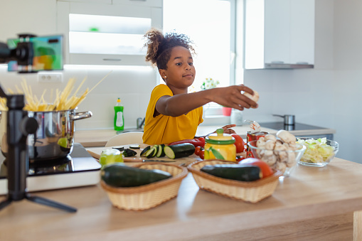 Little black girl cooks in the kitchen at home, With recording making video blogger camera for their blog