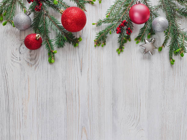 istock Top view on christmas decor. Horizontal border - branches of a Christmas tree, multicolored shiny balls and stars, berries on a light wooden background. Flat lay 1346010140