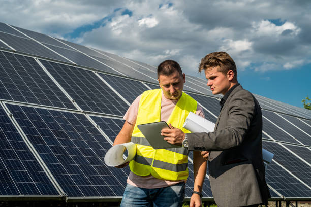 istock Project manager and worker discussing new solar panels installation with blueprints 1346010785