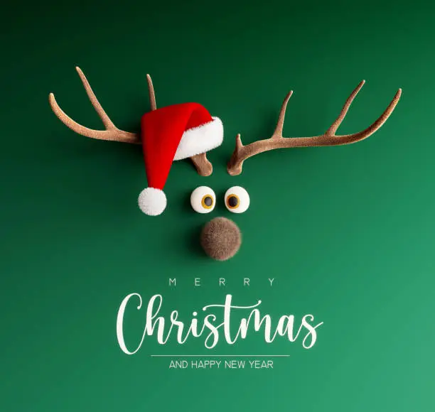 Photo of Reindeer with Santa hat on green Christmas background